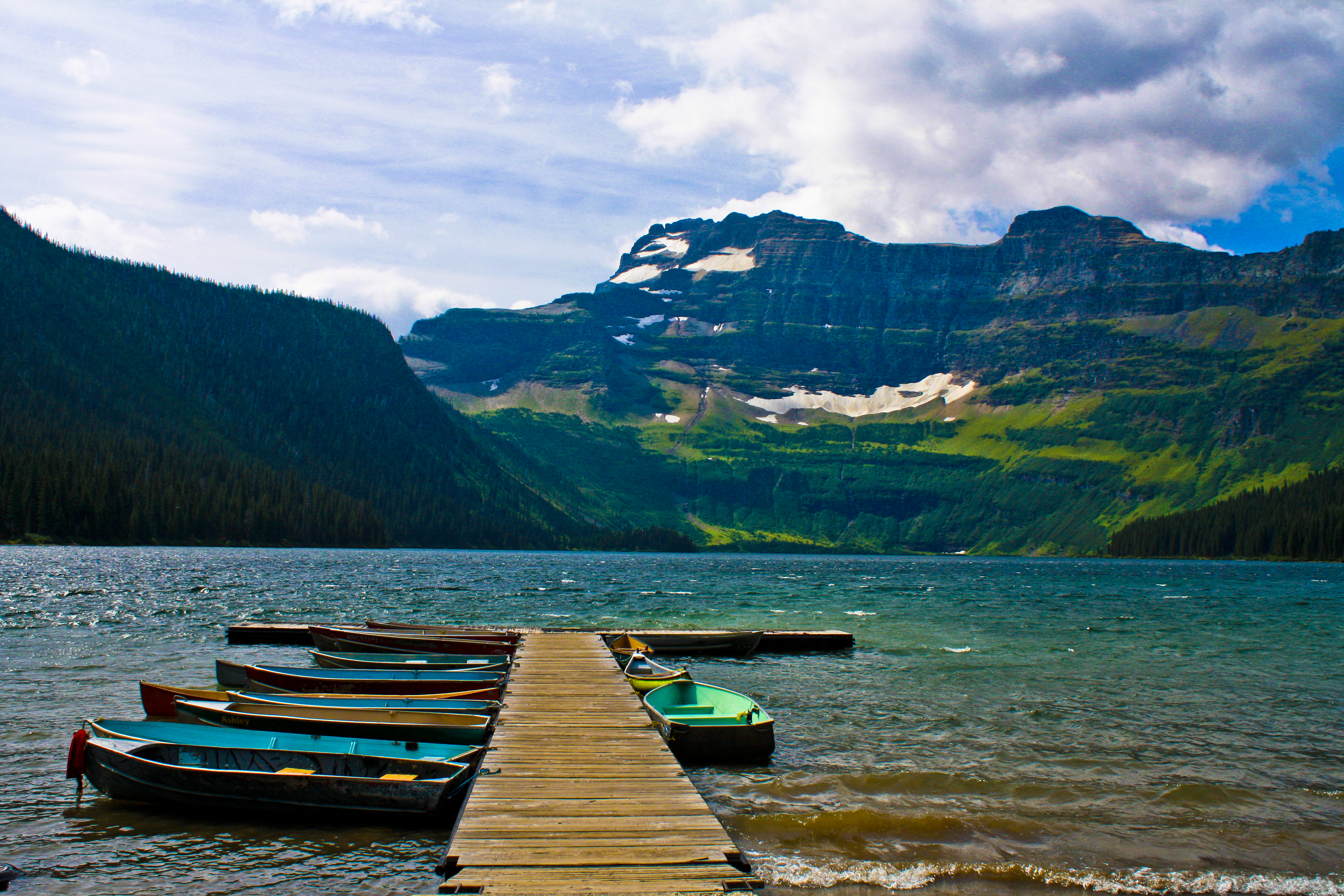 Two colorful canoes tied to a wooden dock on a calm lake.