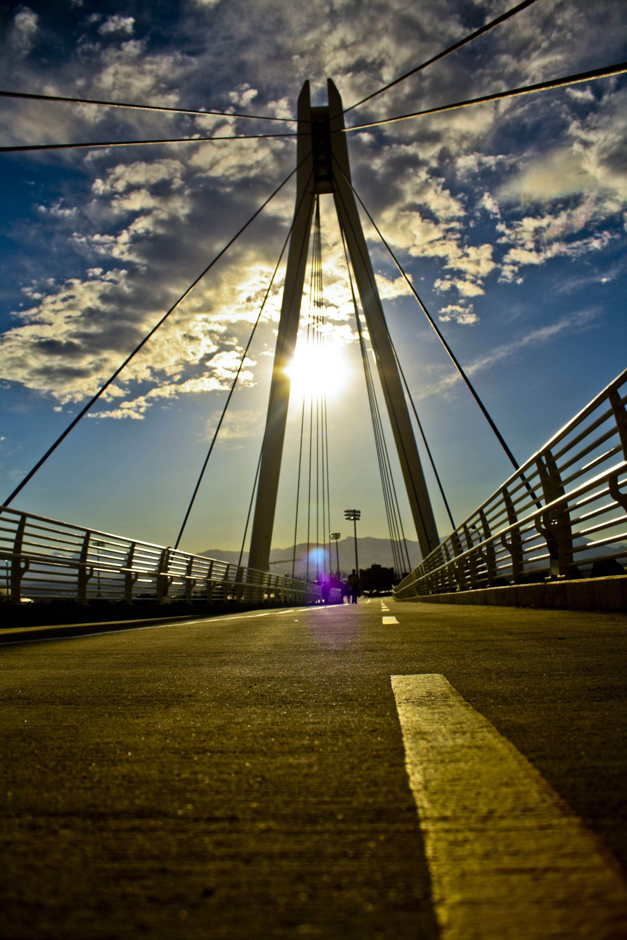 Vibrant sunset over a city bridge with dramatic clouds, titled Highlife.